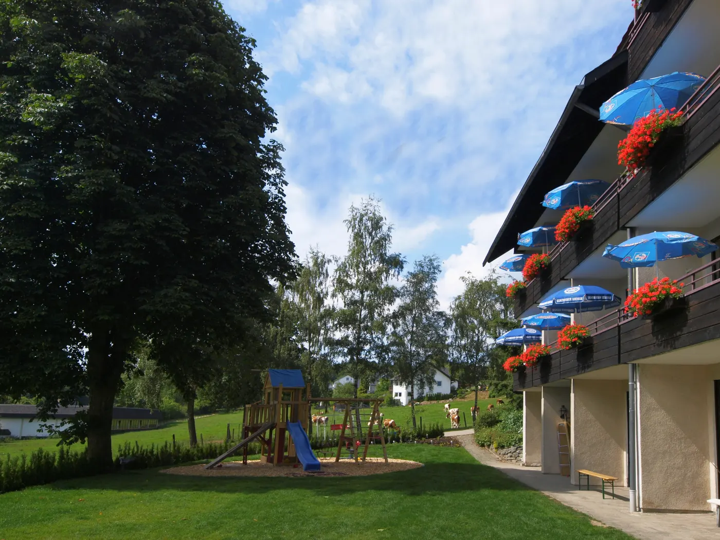 Der Spielplatz im Garten des Landhotel Henkenhof vor dem Haus mit Balkonen