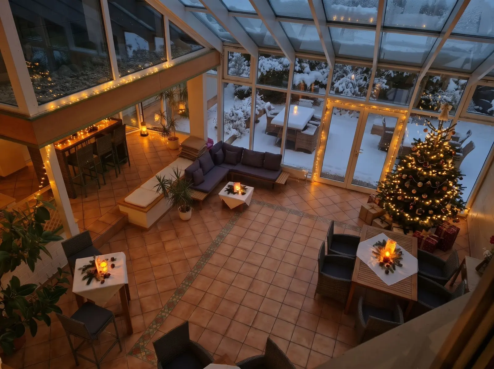 Der festlich geschmückte Wintergarten mit Weihnachtsbaum, Lichterketten und Blick in den verschneiten Garten