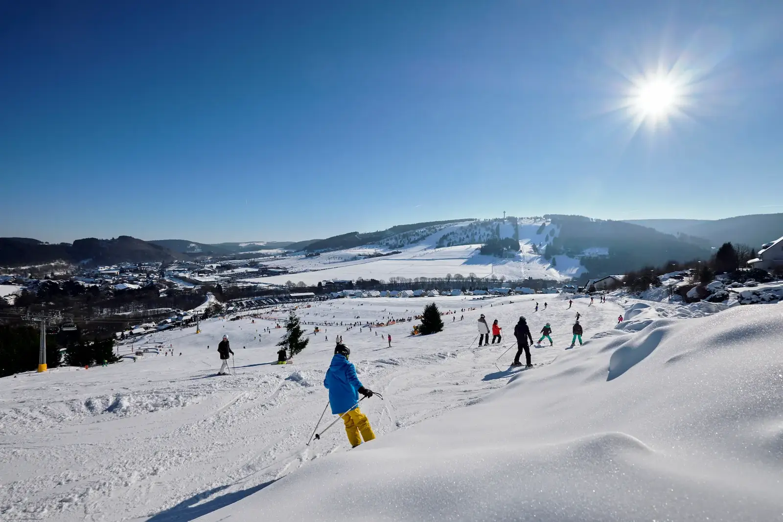 Skifahrer auf sonniger Piste im Skigebiet Willingen mit Blick über das verschneite Tal